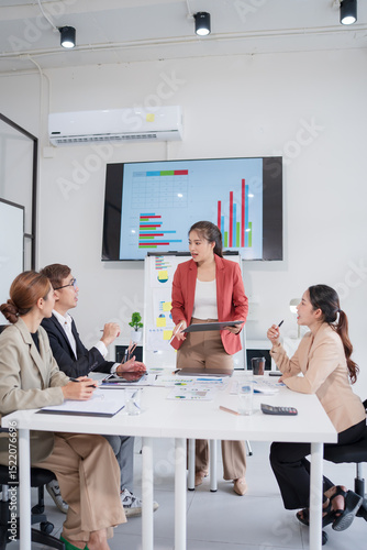 Group of Asian business people presenting their work on a board or on a tablet.
