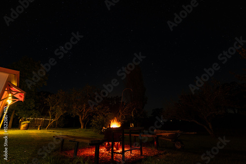 Fotografia Fire pit burning brightly in rural Australian backyard at night under star lit s