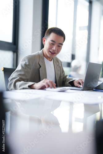 Attractive confident millennial Asian Business man using laptop computer and professional working investor start up project business planning in office.