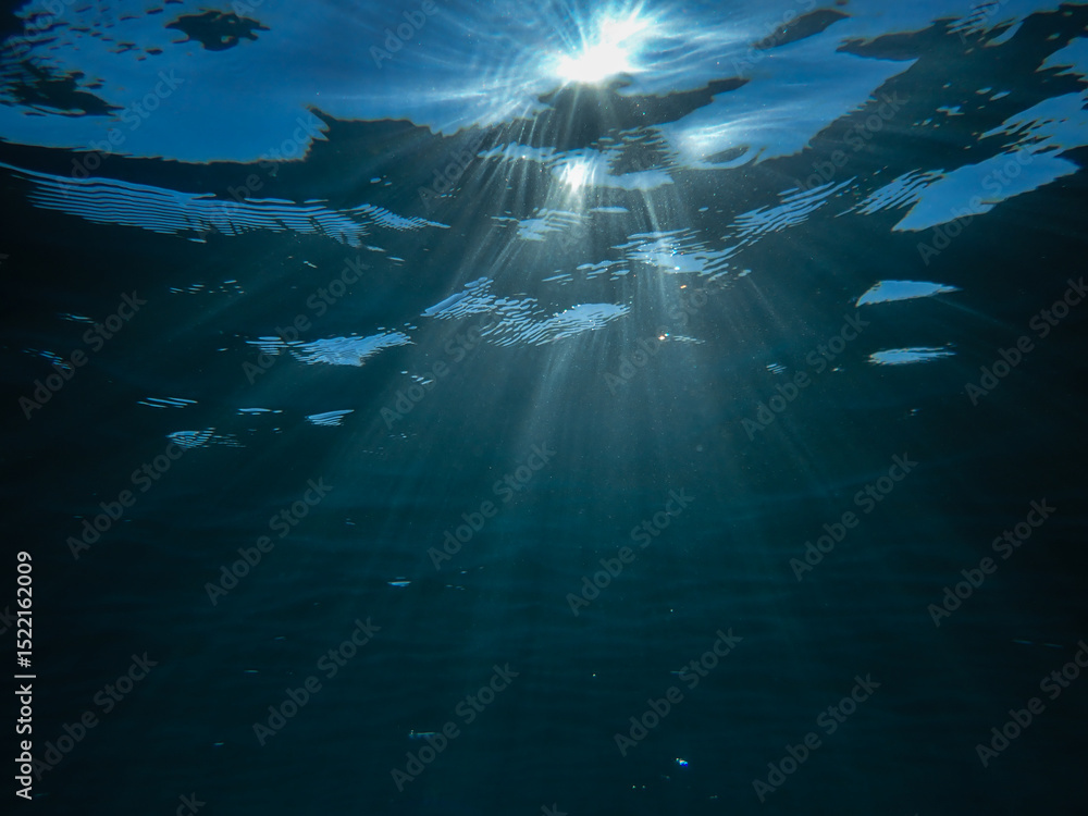 Naklejka premium Ocean blue underwater with sunrays, Underwater Sea Deep Water Abstract Sunshine, sea wave , clean waters in summer time, Natural underwater seascape, sand on ocean floor and water surface with sunligh