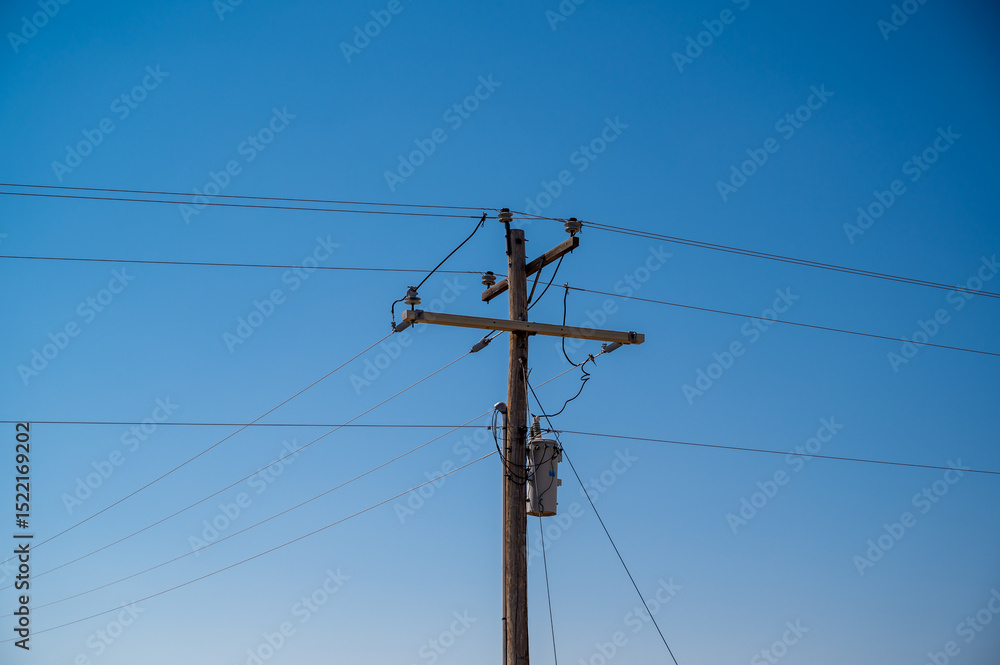 Utility pole stands tall against a clear blue sky in a rural landscape during the afternoon light of late summer Utility pole stands tall against a clear blue sky in a rural landscape during the afternoon light of late summer