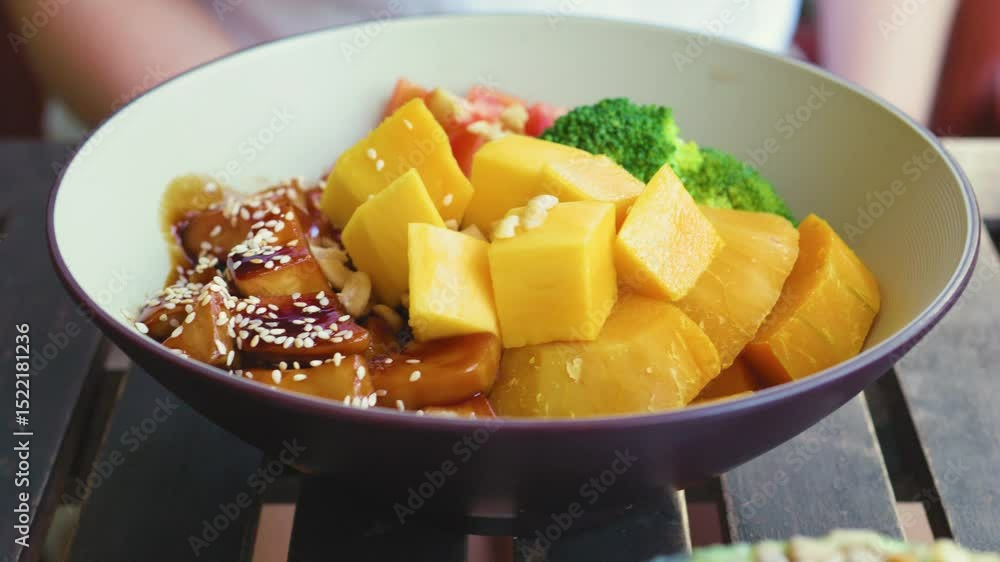 Vegetarian bowl featuring mango, pumpkin, broccoli, tofu drizzled with teriyaki sauce, paired with chilled orange juice Vegetarian bowl featuring mango, pumpkin, broccoli, tofu drizzled with teriyaki sauce, paired with chilled orange juice