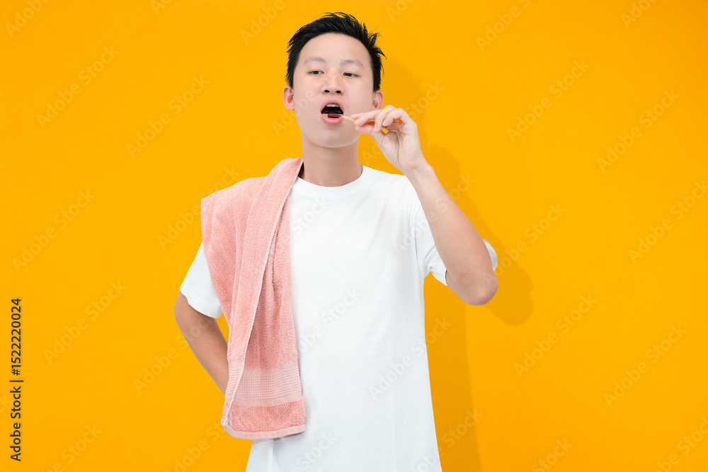 young asian man brushing teeth with towel in isolated orange background young asian man brushing teeth with towel in isolated orange background