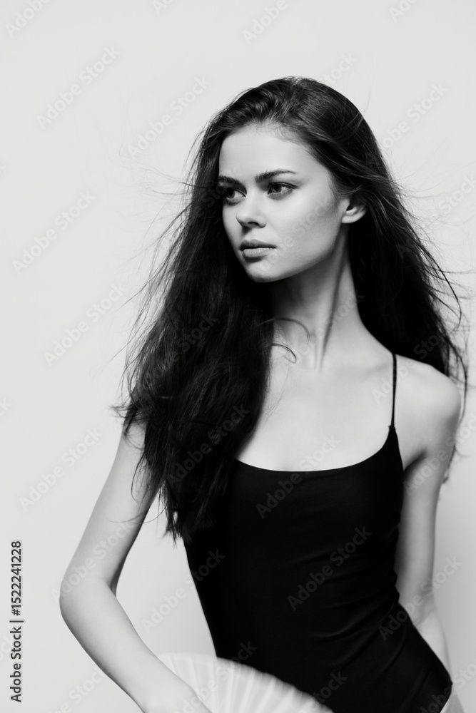 Naklejka premium Elegant model in black bodysuit holding a fan, showcasing graceful poses with flowing hair against a soft white background. Fashion and beauty concept.