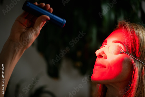 Fototapet Woman wearing a red light therapy face mask during a skincare session, known for boosting collagen, reducing wrinkles, improving skin tone, and promoting facial skin rejuvenation