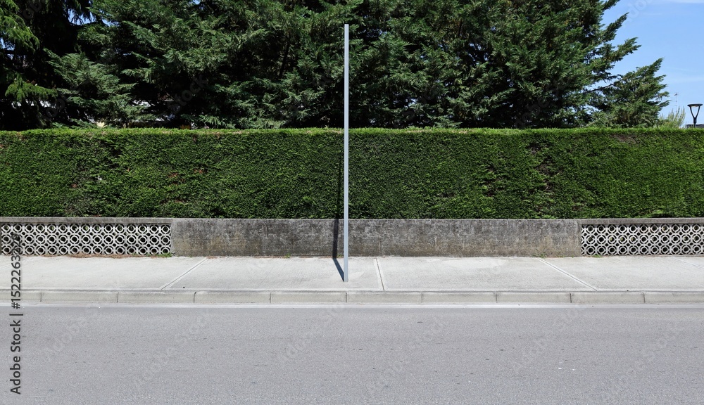 custom made wallpaper toronto digitalMetallic pole on sidewalk with concrete fence, hedge and trees on behind. Street in front. Background for copy space.