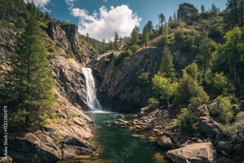 Best Waterfall Hikes in National Parks. Majestic waterfall flowing into a serene pool surrounded by rocks, pine trees, and mountains under a clear blue sky in natural setting.