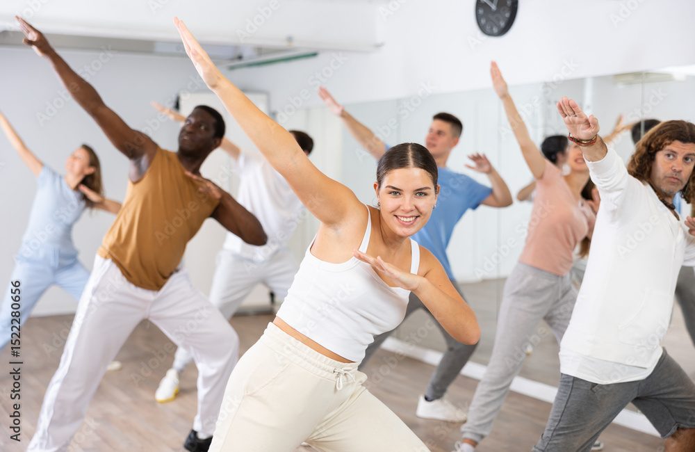 Naklejka premium Group of active women and men practicing energetic dance in a modern dance studio