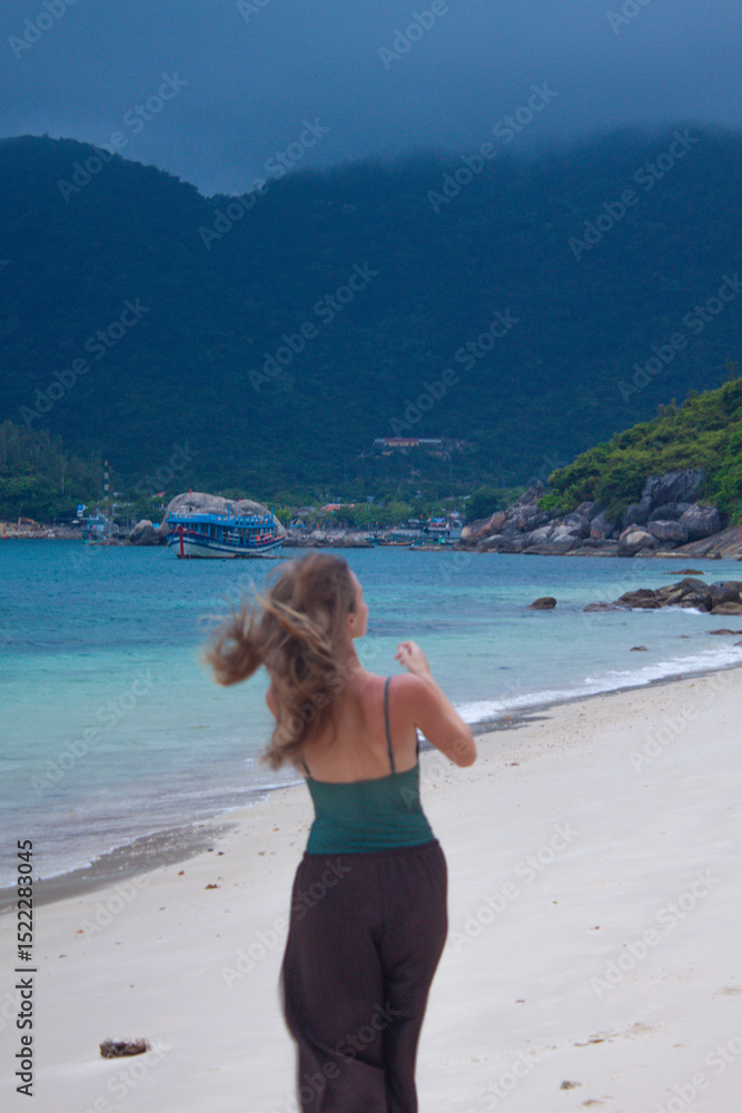 Back view of woman walking along tropical beach.
Back view of woman walking along tropical beach.