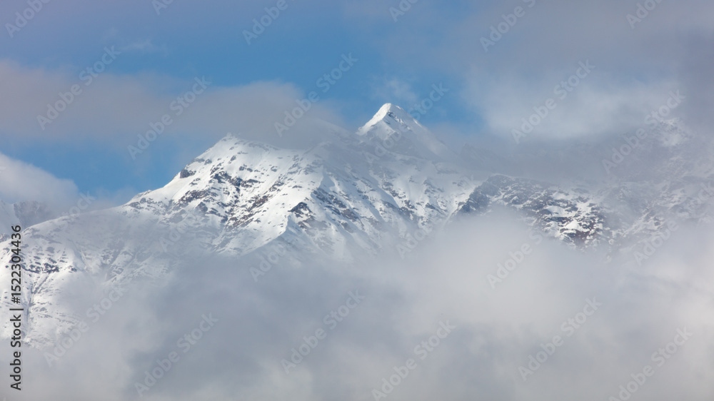 Obraz premium A mountain covered in snow with a cloudy sky in the background