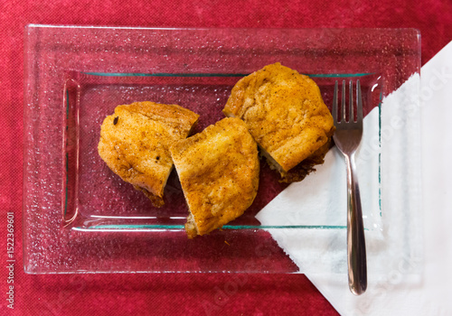 Top view of sweet Madrid torrijas served on glass plate on burgundy background. Spanish cuisine
