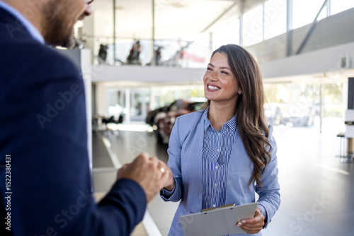 Confident sales team in dealership, two beautiful consultants or managers in black full suit with crossed arms looking on camera