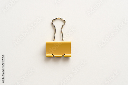 Minimalist image of a single yellow binder clip on a white textured background. Clean, simple, and modern stationery concept.