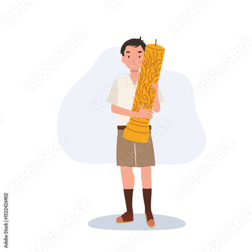thai schoolboy holding large wax candle for buddhist holiday celebration in thailand cultural festival and asian tradition.