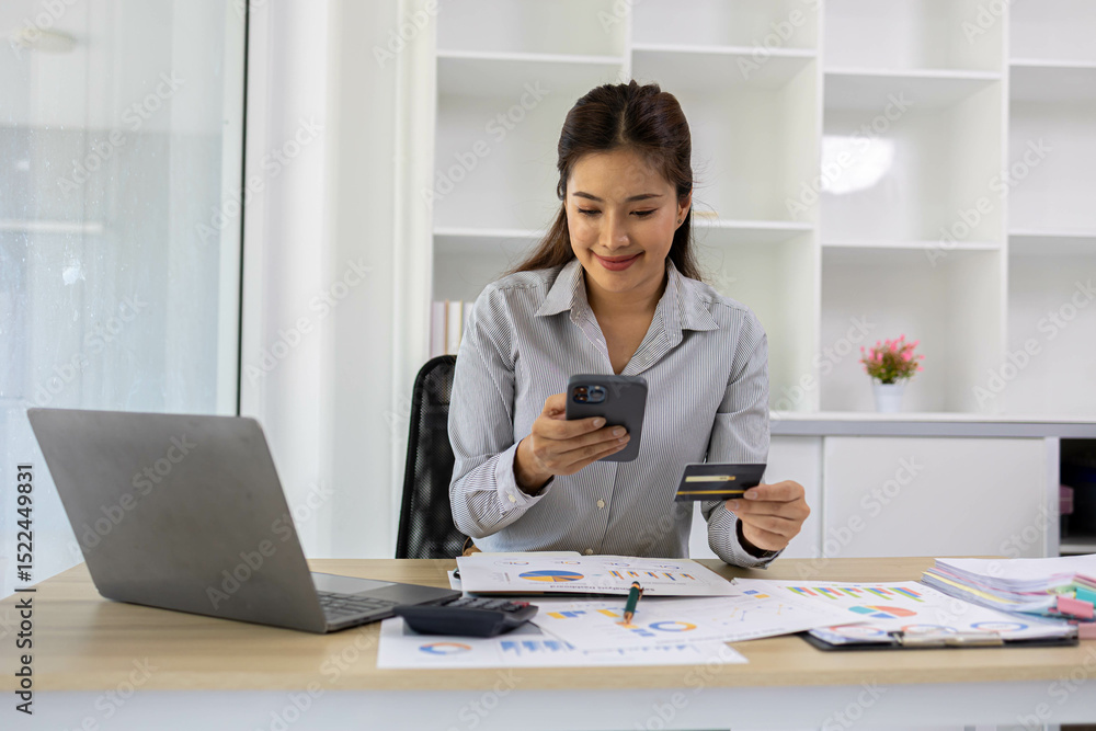 A woman is sitting at a desk with a laptop and a cell phone. She is looking at her cell phone and she is checking something. The desk is cluttered with papers and a calculator
A woman is sitting at a desk with a laptop and a cell phone. She is looking at her cell phone and she is checking something. The desk is cluttered with papers and a calculator