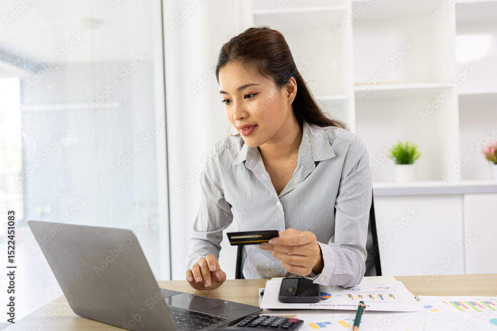 A woman is sitting at a desk with a laptop and a cell phone. She is looking at her cell phone and she is checking something. The desk is cluttered with papers and a calculator
A woman is sitting at a desk with a laptop and a cell phone. She is looking at her cell phone and she is checking something. The desk is cluttered with papers and a calculator