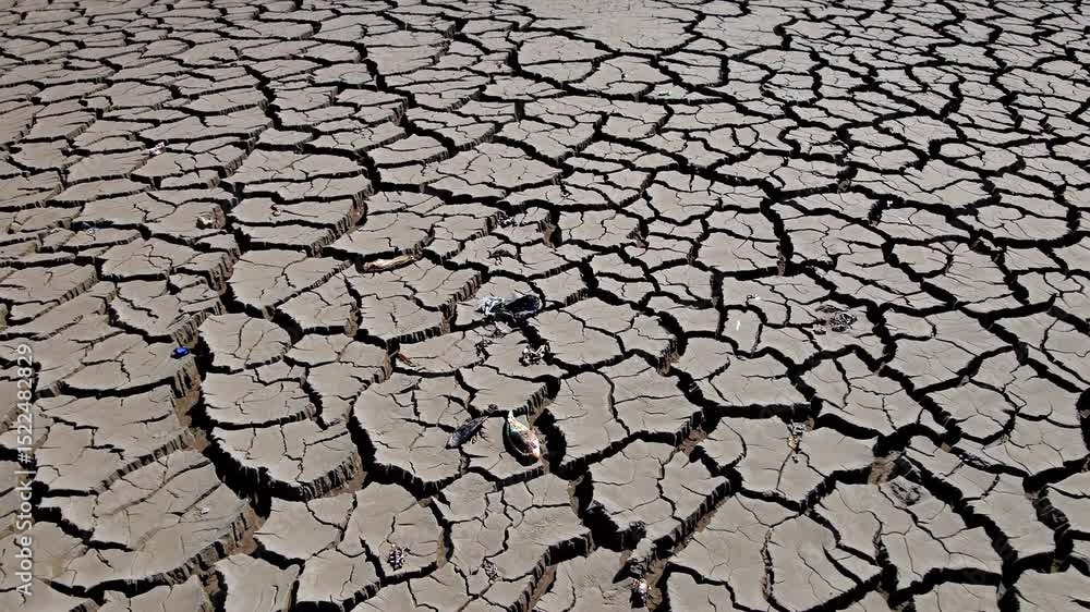Cracked lakebed revealing abandoned, weathered vessels, stark testimony of prolonged drought impacting ecosystem sustainability Cracked lakebed revealing abandoned, weathered vessels, stark testimony of prolonged drought impacting ecosystem sustainability
