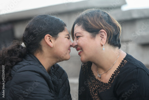 Obraz na płótnie closeup portrait of mid adult hispanic mother with her teenage daughter nose to