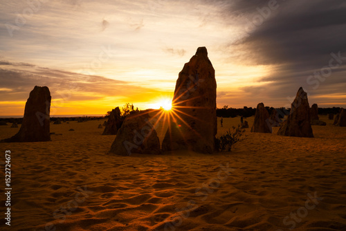 Golden sunset light with a sunburst on the Pinnacles, an area of limestone pillars in Nambung National Park, Western Australia.