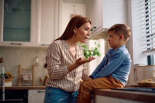 Mother scolding her son in kitchen.