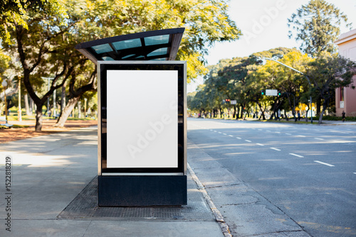A vertical blank billboard at a bus stop shelter in Buenos Aires, Argentina along Libertador avenue in autumn. Copy space poster into a lightbox to display advertising content.