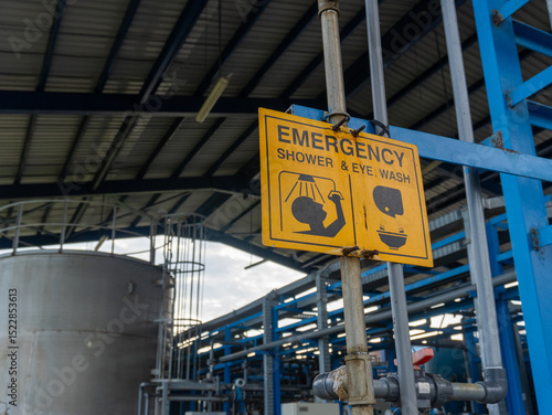 Yellow emergency shower and eye wash sign in the chemical industry area. Wash the part that is exposed to the chemical