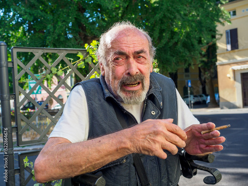 older caucasian man sits on medical walker outdoors, smoking a cigar in public despite visible signs of frailty, illustrating contrast between age-related vulnerability and risky personal habits.