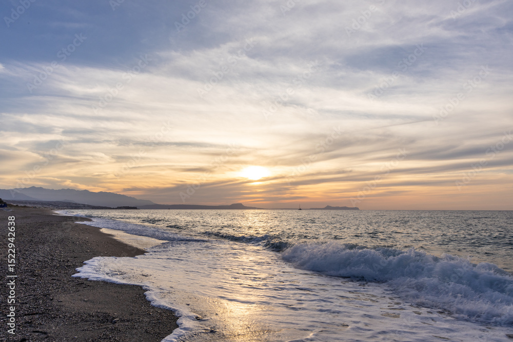 Beautiful coastline with a sandy and pebble beach at sunset. Beautiful sky coloration in the tourist and hotel area of Platanes Beach, Rethymno, Crete, Greece Beautiful coastline with a sandy and pebble beach at sunset. Beautiful sky coloration in the tourist and hotel area of Platanes Beach, Rethymno, Crete, Greece