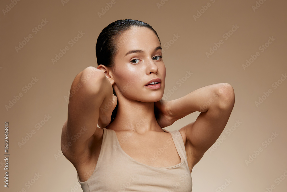 Obraz premium Young female model displaying healthy skin and natural beauty, posing with her hands in a minimalist setting, emphasizing skincare and self care
