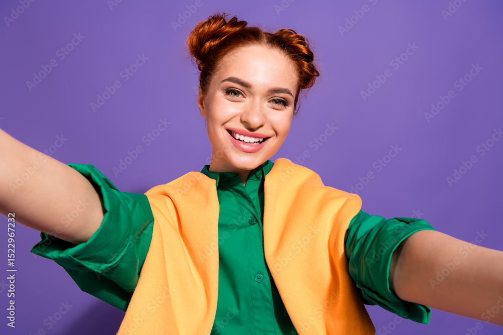 Charming young woman with red hair wearing green shirt smiling against vibrant purple background, carefree pose Charming young woman with red hair wearing green shirt smiling against vibrant purple background, carefree pose