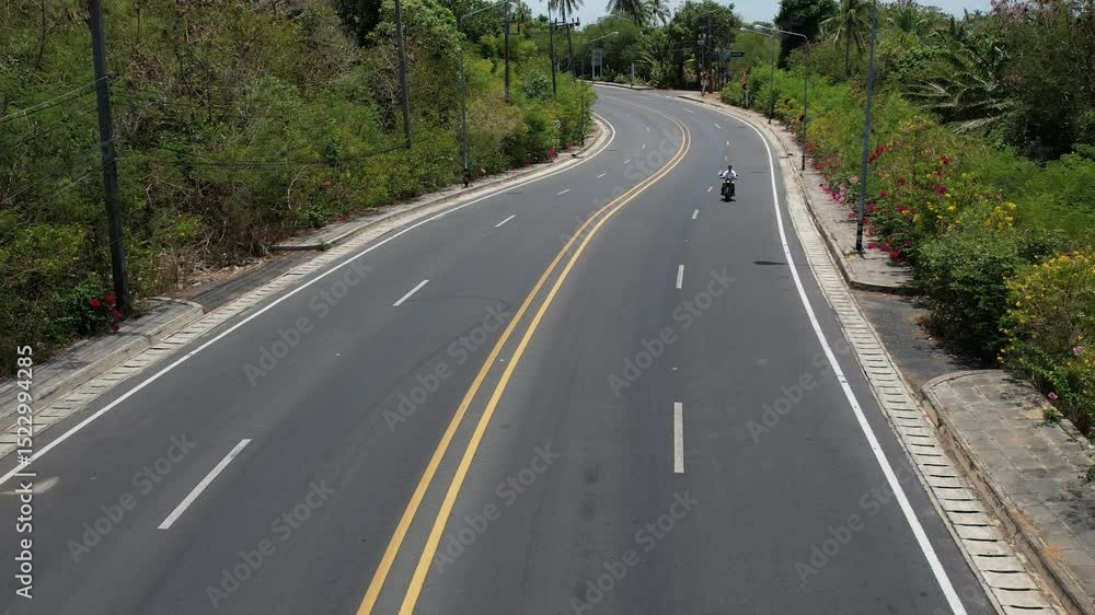 Man rides a motorcycle along a winding tropical island road, with ocean views and nearby islands, captured by drone. Scenic and adventurous. Man rides a motorcycle along a winding tropical island road, with ocean views and nearby islands, captured by drone. Scenic and adventurous.