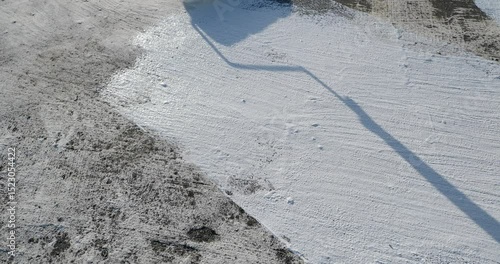Painter applying a fresh white waterproof coat paint with a roller tool to a roof surface.