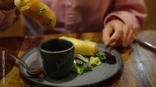 Young Asian woman eating Po Pia Tawd ( crispy Thai spring rolls stuffed with rice vermicelle and vegetables) 