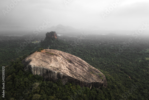 Aerial rising view visitors hiker on top viewpoint of Pidurangala Rock with Sigiriya rock view and the lush green jungle in Sri Lanka Cultural Triangle