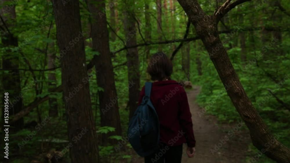 Beauty emotion woman with backpack walking on path in a green forest along. Relax girl hiking in wood and looking around on trees on sunny summer day. Person coming in style fashion clothes. Beauty emotion woman with backpack walking on path in a green forest along. Relax girl hiking in wood and looking around on trees on sunny summer day. Person coming in style fashion clothes.