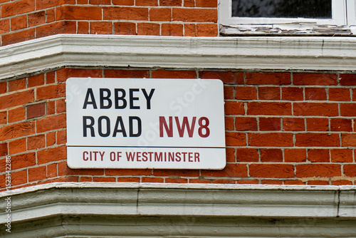 White street sign for Abbey Road NW8, City of Westminster, fixed on a red brick wall, marking a famous music location in London