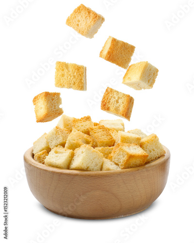 Fotografi Delicious crispy croutons falling into bowl on white background