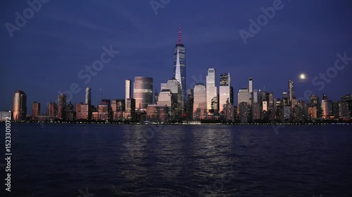 nyc skyline view of downtown manhattan skyscrapers at sunset dusk blue hour (glow glowing reflection from buildings) moving water flowing hudson river moonrise moon shining last light buildings nj