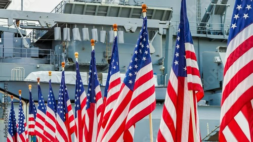 American flags waving proudly in the wind, creating a vibrant display of patriotism, while a powerful warship looms in the background, symbolizing military strength and national pride