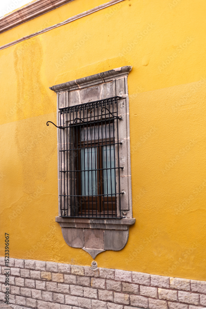 Obraz premium Ventana vertical antigua con muro de piedra enmarcada. Espacio viejo, exterior de casona colonial mexicana. Hacienda historica. Muro amarillo.