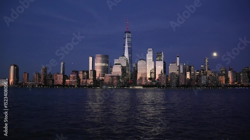 nyc skyline view of downtown manhattan skyscrapers at sunset dusk blue hour (glow glowing reflection from buildings) moving water flowing hudson river moonrise moon shining last light buildings nj