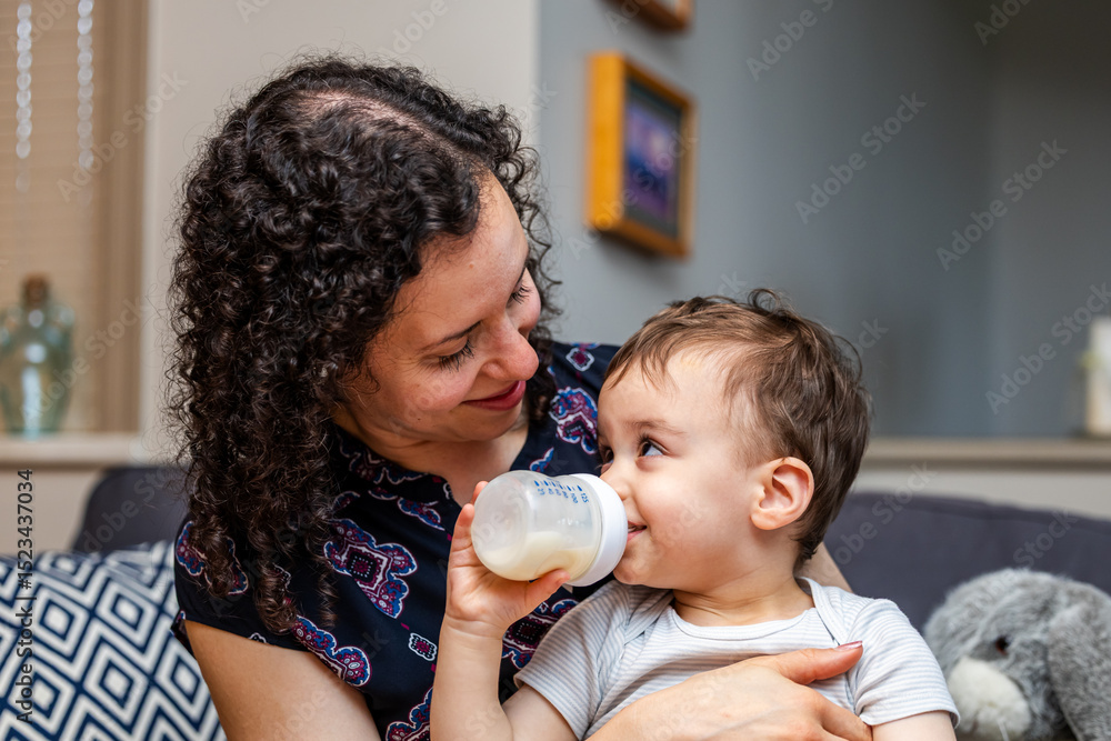 Loving Mother Holding Her Boy Toddler Who Is Drinking a Milk Bottle Loving Mother Holding Her Boy Toddler Who Is Drinking a Milk Bottle