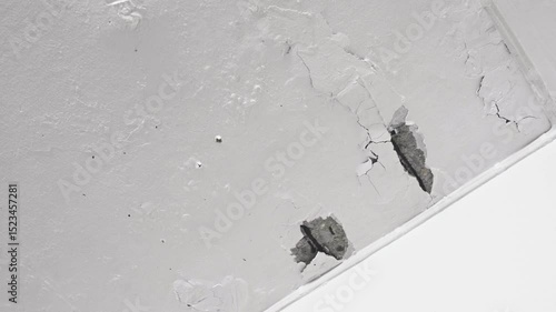 The ceiling and walls of the house are moisture damaged, with peeling paint, cracks, and rough surfaces. The plaster to erode and peel off.