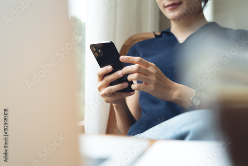Canvas Print Woman using mobile phone and laptop checking email or news online while sitting at home