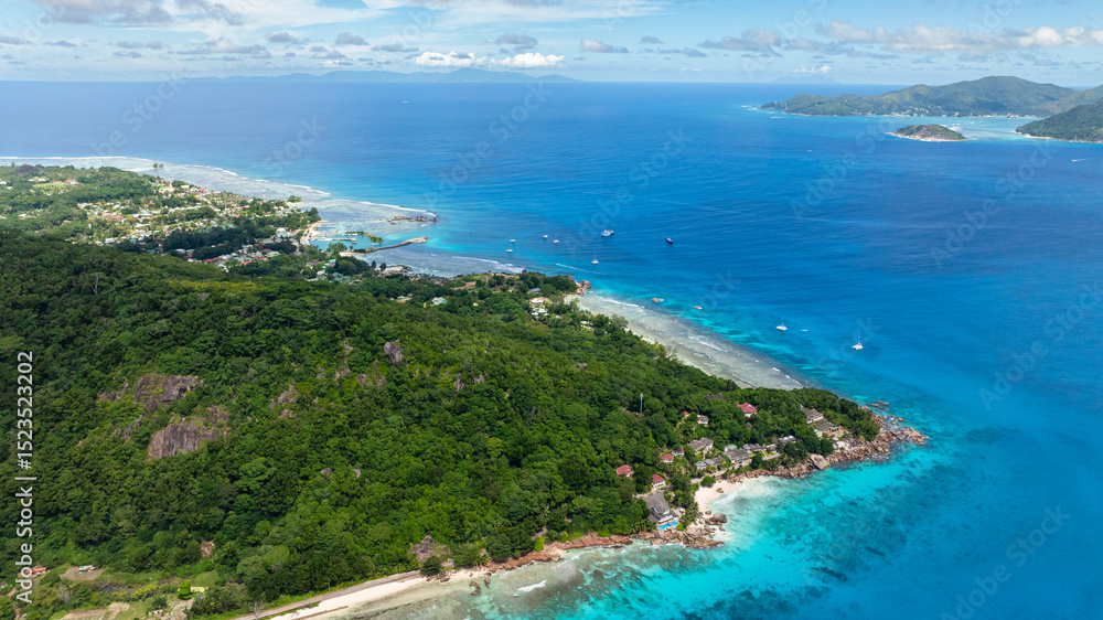 Island with lush green hills and turquoise ocean waters, viewed from above. La Digue, Seychelles. Island with lush green hills and turquoise ocean waters, viewed from above. La Digue, Seychelles.
