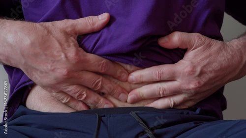 A man rubs his stomach in pain.