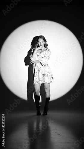 Fashion model showing how to pose, studio shot under the spotlight