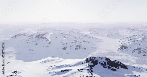 Vast snow covered mountains rise under a clear sky, creating a serene arctic landscape. The rugged terrain showcases the beauty of nature in its untouched form.