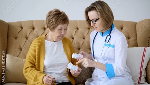 Tableau sur toile Female doctor is sitting next to an elderly woman on a sofa, carefully explainin