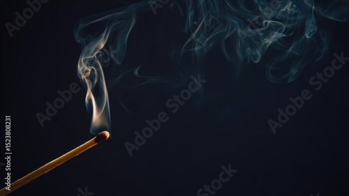 Matchstick burning and producing smoke in dark setting